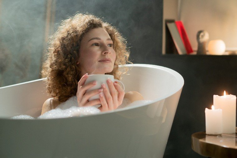 Slečna vychutnávající si horký nápoj v pěnové koupeli